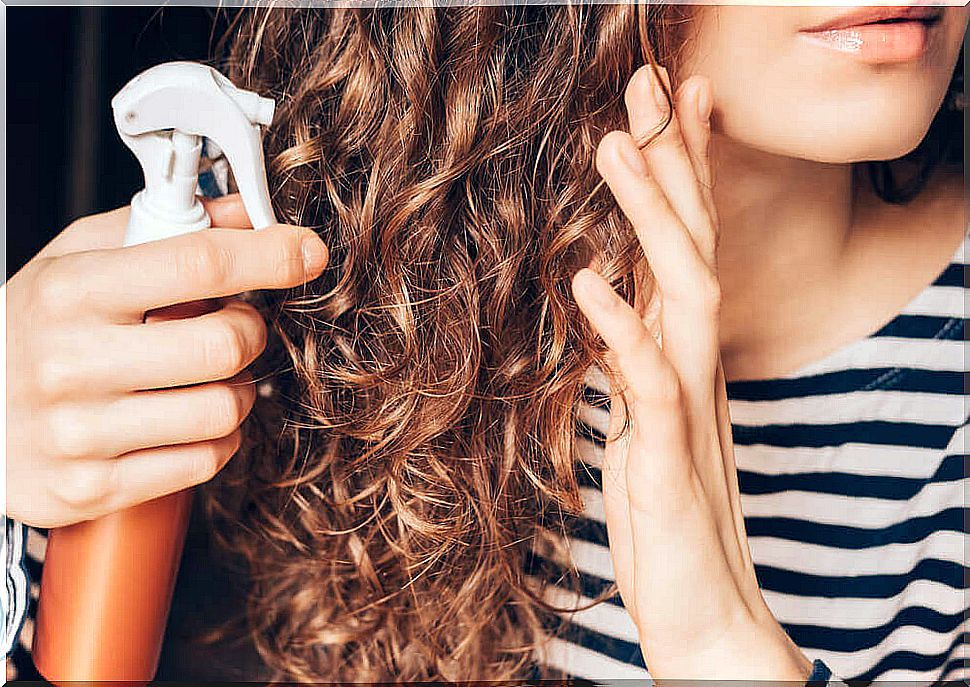 Girl applying coconut oil to her hair.